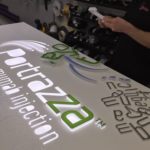 Inspecting an acrylic letter prior to being glued into a routed aluminium tray with opal acrylic diffuser
