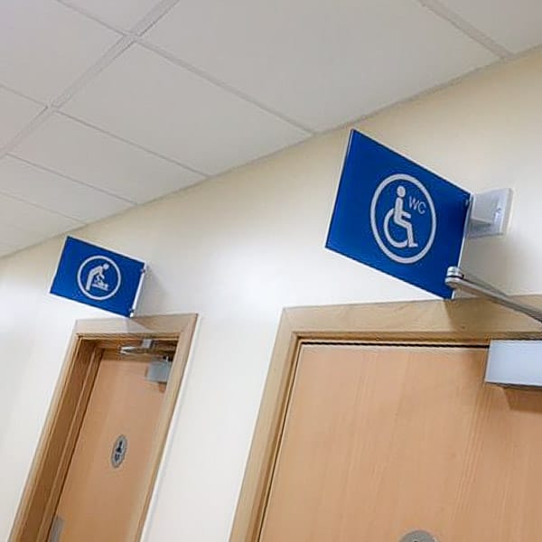 Double sided projecting sign giving directions to toilets