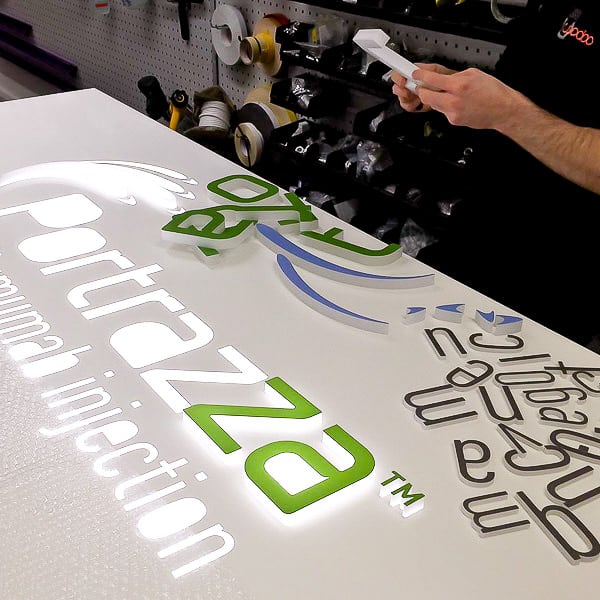 Inspecting an acrylic letter prior to being glued into a routed aluminium tray with opal acrylic diffuser