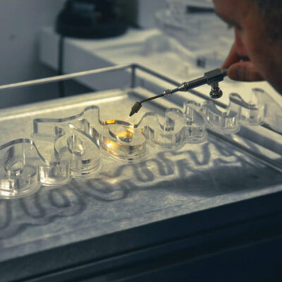 A skilled Voodoo employee flame polishing 20mm clear acrylic lettering